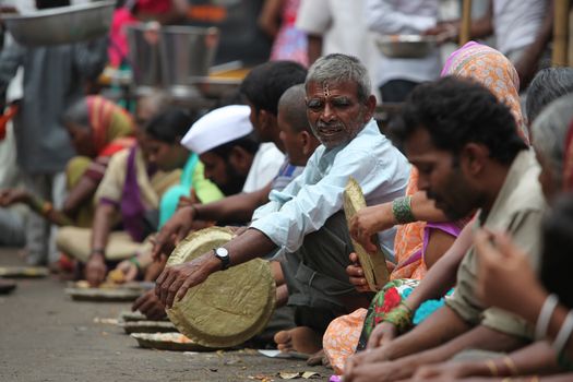 Pune, India - July 11, 2015: Hungry pilgrims called warkaris wait to be served on the streets during the famous wari pilgrimmage in India.
