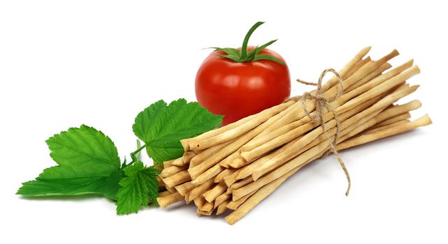 Crispy crunchy long bread sticks with tomato and green leaf, isilated on a white background.
