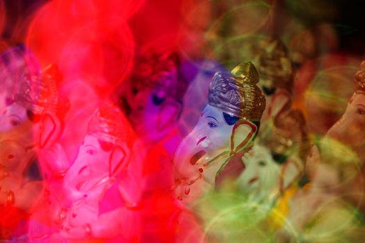 A view of traditional Ganesha idols through blur colorful lights during Ganapati festival