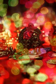 Brass idols of hindu gods during festival, behind blur colorful lights.