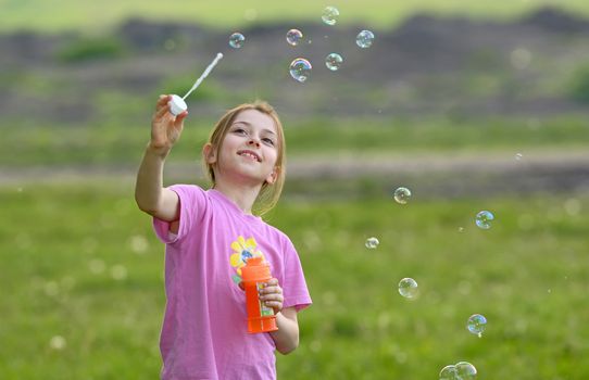 little girl play with soap bubbles on field