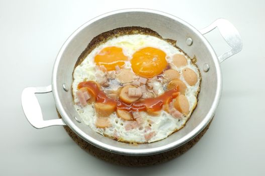 Fried egg with ham and sausage in a pan