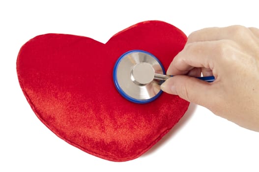Heart shaped pillow with hand holding stethoscope on white background