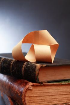 Paper Mobius strip on old books against dark background