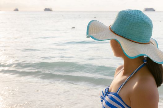 Young girl wearing a hat and swimsuit standing watch nature sky and sea during the sunrise on beach of Honeymoon Bay at Koh Miang, Similan Islands National Park, Phang Nga, Thailand