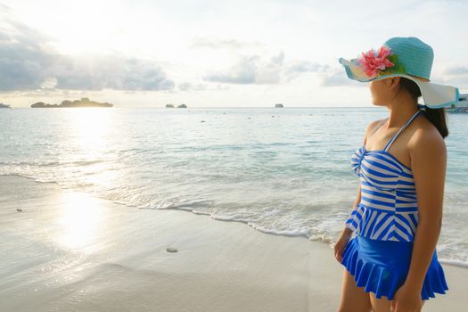 Young girl wearing a hat and swimsuit standing watch nature sky and sea during the sunrise on beach of Honeymoon Bay at Koh Miang, Similan Islands National Park, Phang Nga, Thailand