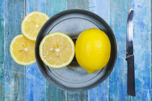 Sliced lemons with knife isolated on blue wood background.