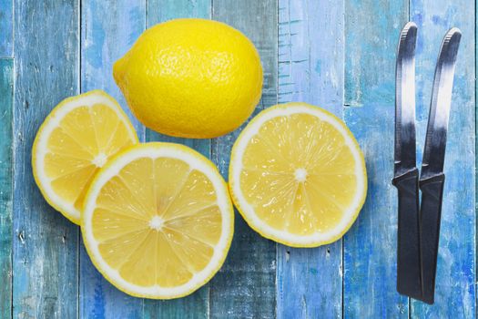 Sliced lemons with knife isolated on blue wood background.