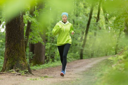 Sporty young female runner in forest.  Running woman. Female runner during outdoor workout in nature. Fitness model outdoors. Weight Loss. Healthy lifestyle. 