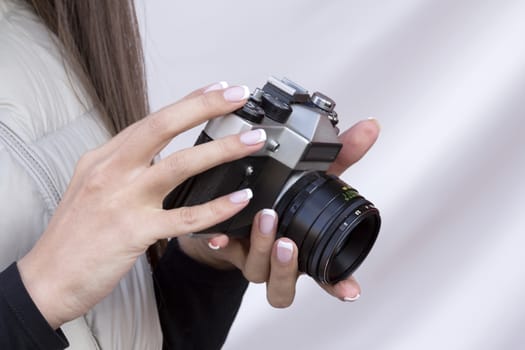 the girl with the French manicure is holding the vintage  camera