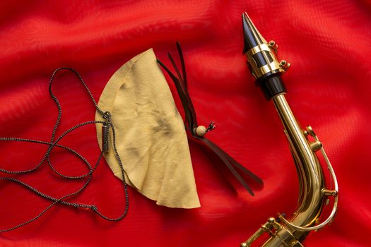Suede brush and saxophone mouthpiece on a red background
