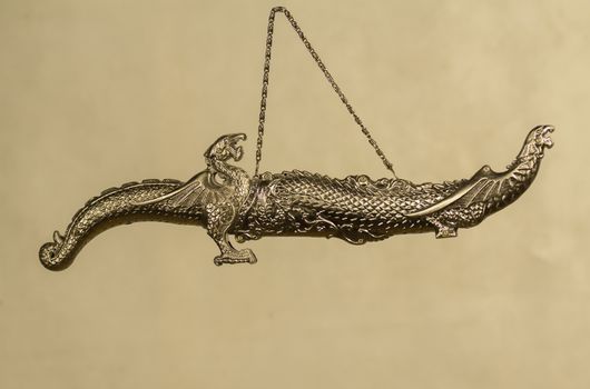 decorative carved dagger with heads of dragons in a sheath on a gray background