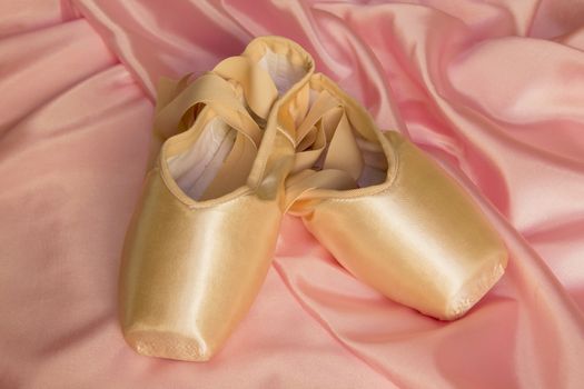 Ballet shoes on silk pink background
