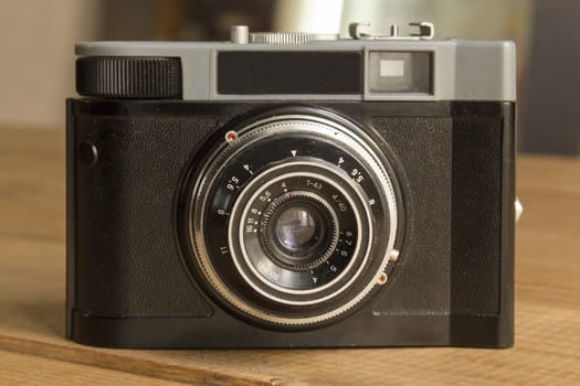 Black retro film camera on wooden background