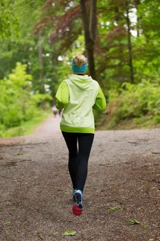 Sporty young female runner in forest.  Running woman. Female runner during outdoor workout in nature. Fitness model outdoors. Weight Loss. Healthy lifestyle. 