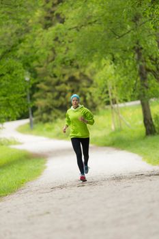 Sporty young female runner in city park.  Running woman. Female runner during outdoor workout in nature. Fitness model outdoors. Weight Loss. Healthy lifestyle. 