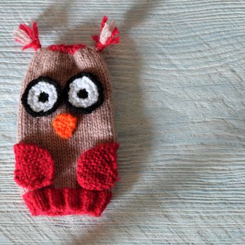 Hand puppets for children day, colorful owl puppet knit from yarn, funny handmade gift for child day on white wooden background