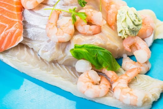 Various raw fish species as fillets like salmon, cod and shrimp.