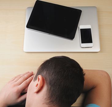 Man sleep at work on wood table with gadgets