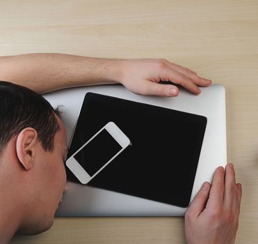 Guy sleeping and give hug to laptop on wood table