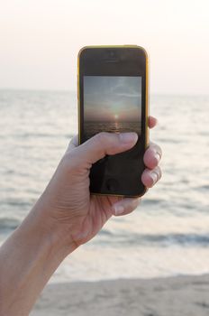 woman hands holding mobile phone at sunset