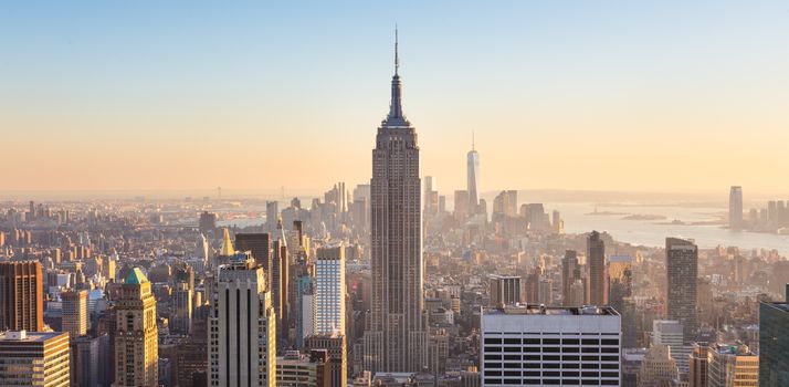 New York City. Manhattan downtown skyline with illuminated Empire State Building and skyscrapers at sunset seen from Top of the Rock observation deck. Vertical composition.