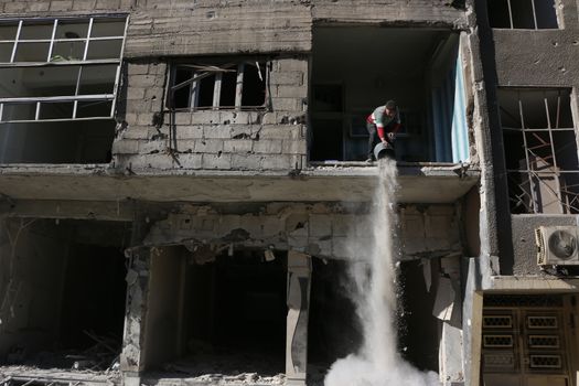SYRIA, Saqba : A resident of the city of Saqba cleans a destroyed building of the city of East suburb of Damascus, the capital city of Syria, on December 28, 2015. Regime forces fired rockets on the towns of Douma, Harasta, Saqba and Arbin in the opposition-held Eastern Ghouta region on December 13, 2015 according to the Syrian Observatory for Human Rights. At least 45 people were killed during these attacks, according to the NGO. 