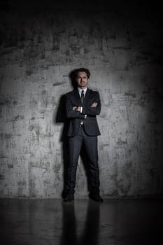 Full length portrait of a businessman in suit over concrete wall background