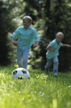 Happy children playing football in summer park