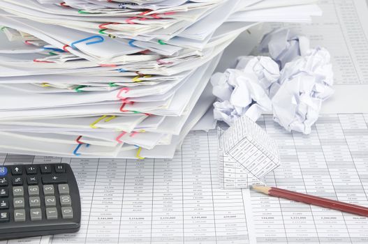 Bankruptcy of house with pencil on finance account have blur paper ball and overload document of report and receipt with colorful paperclip place confused and calculator as background.