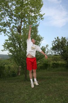 Young man in red and white playing fresbee in nature