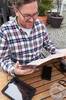 Young traveller man with glasses and a hat  looking for a place in a map looking up