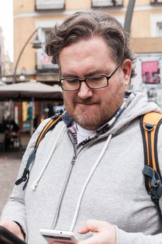 Young man with glasses in looking his mobile device