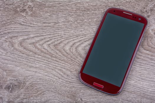 Red mobile phone on a brown wooden background