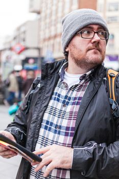 Young traveller man with glasses and a hat  looking for a place in a map looking up