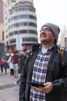 Young traveller man with glasses and a hat  looking for a place in a map looking up