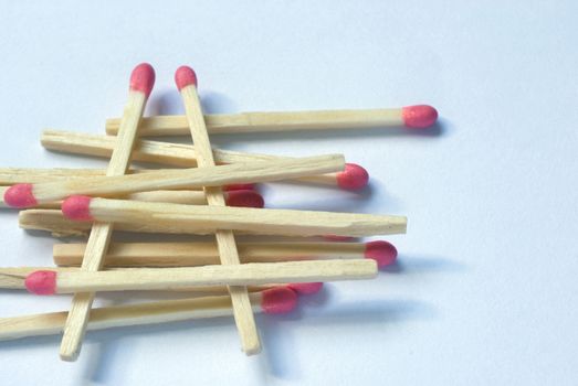 Numerous new wooden match sticks stacked one upon the other over white background