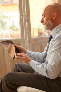 Businessman middle-aged bearded and suit jacket searching on tablet on a blurred background