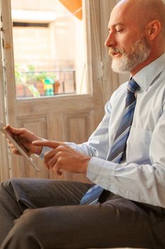 Businessman middle-aged bearded and suit jacket searching on tablet on a blurred background