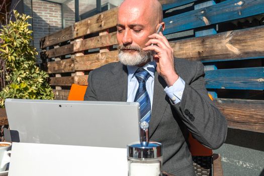 Middle-aged man , handsome and elegant working outside the office in a relaxed atmosphere