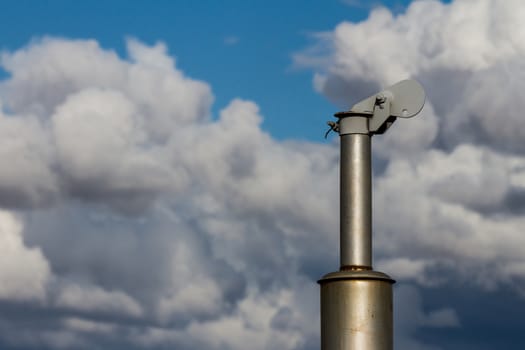 View of a pipe off an old farm tractor against clouds in the sky. showing what could be pollution or global warming