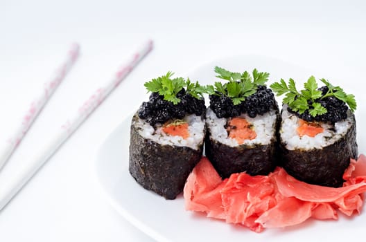 Rolls with salmon, caviar and pickled ginger, decorated with greens on a white background and white background. In the morning, and bokeh.