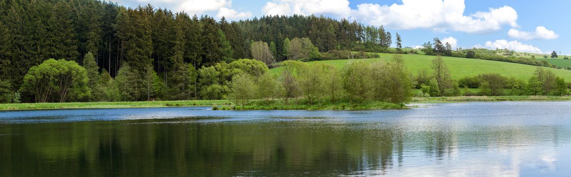 Beautiful summer rural landscape with small lagoon. Rural landscape with pond. Spring landscape. Green czech countryside. Beautiful highland vysocina european countryside