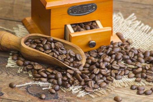  coffee grinder on wooden background with roasted coffee beans