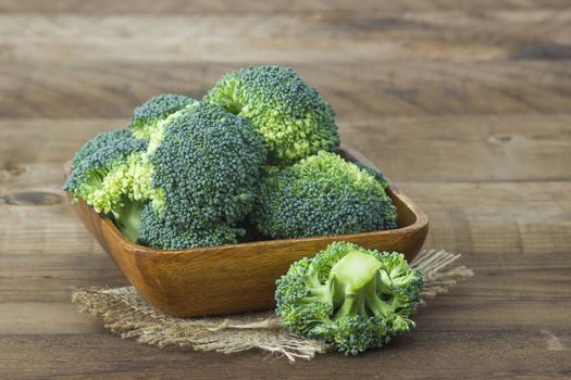 Raw broccoli in a bowl on wooden background