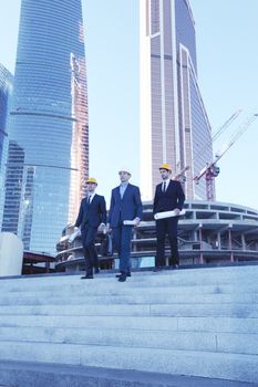 Architects with blueprint at skyscrapers background