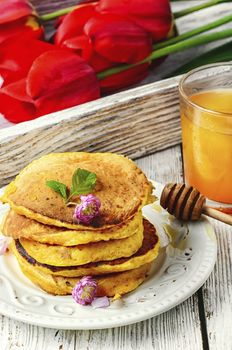 Pumpkin pancakes with glass of the juice and flowers to the morning breakfast