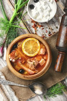 Traditional solyanka with smoked meats in wooden plate