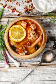 Traditional solyanka with smoked meats in wooden plate
