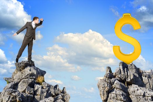 Young businessman standing on edge of rock mountain and looking at dollar sign